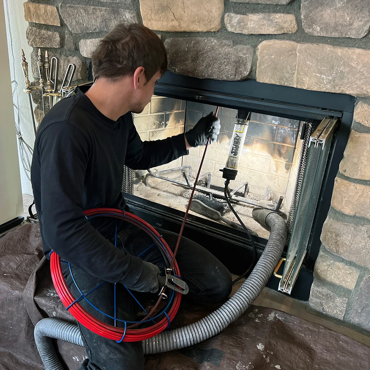 Technician using inspection equipment inside a stone fireplace